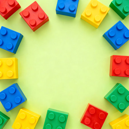 Top view of colorful plastic building blocks on green background with copy spaceの写真素材