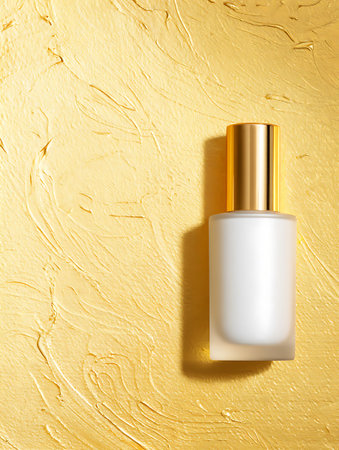 White cosmetic bottle on golden background. Top view with copy space.の写真素材
