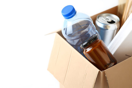 Recycling plastic bottles and cans in cardboard box on white background