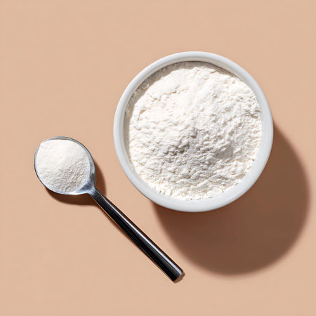 Flour in a bowl and spoon on a beige background, top view