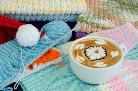 A cup of latte art on a knitted vest backgroundの写真素材