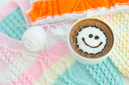 A cup of latte art on a knitted vest backgroundの写真素材