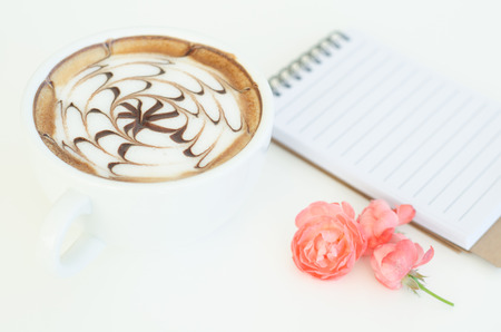 a cup of latte art and rose on white backgroundの写真素材