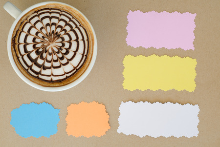a cup of latte art and note paper on brown paper backgroundの写真素材