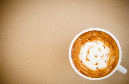 a cup of latte art on brown paper background, vintage style