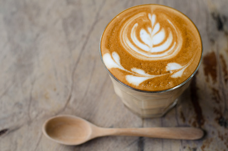 a glass of hot latte art coffee on wooden tableの写真素材