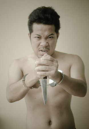 Men in handcuffs holding knife in handの写真素材