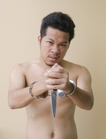 Men in handcuffs holding knife in handの写真素材