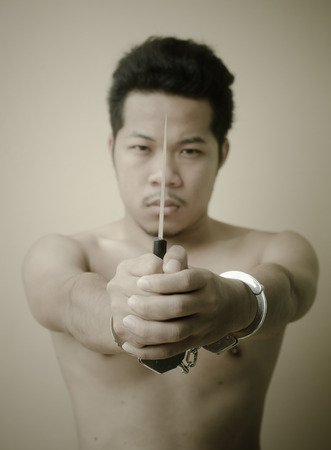 Men in handcuffs holding knife in handの写真素材
