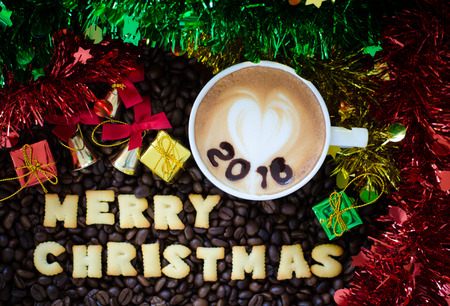 latte art coffee and alphabet "merry christmas" made from bread cookies on coffee beans backgroundの写真素材