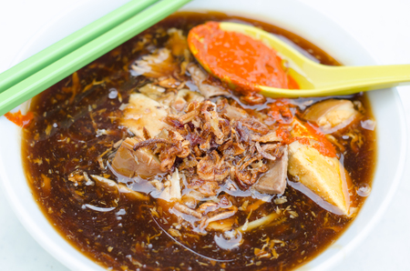 A bowl of Loh mee with chopsicks and a spoonful of chili pasteの写真素材