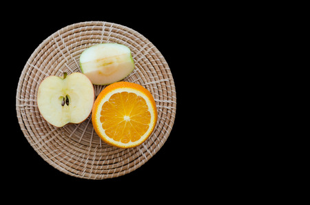 apple and orange sliced on wooden plate isolated on black backgroundの写真素材