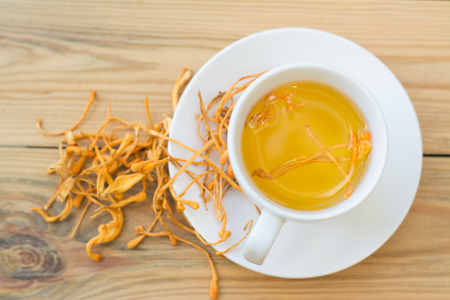 Dried Cordyceps Militaris Mushroom with Cup on wooden table backgroundの写真素材