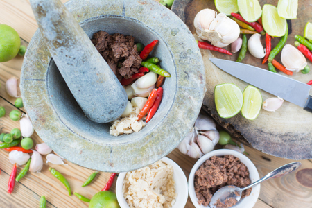 Prepare ingredient inside the stone mortar and grinding for spicy shrimp paste chilli sauce, Thai foodの写真素材