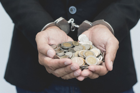 Man hands in handcuffs with thai coins. arrest steal money conceptual.の写真素材