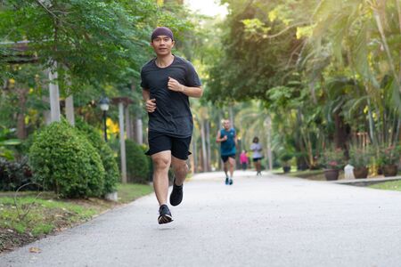 Young athletic man running at park during spring morningの写真素材