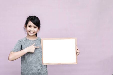 Little asian girl holding whiteboard isolated on gray background.の写真素材