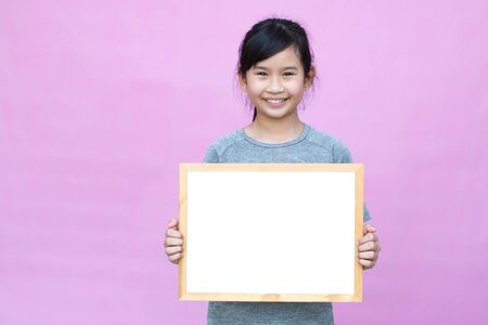 Little asian girl holding whitekboard isolated on pink background.の写真素材
