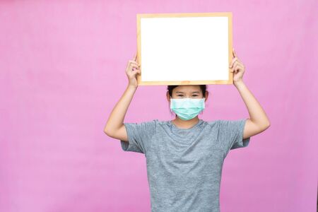 Little asian girl holding whiteboard isolated on pink background.