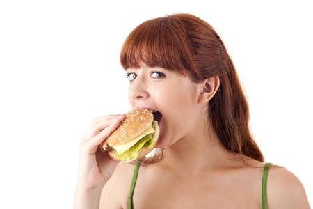 Young attractive woman eating hamburger on white backgroundの写真素材