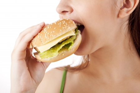 Young attractive woman eating hamburger on white backgroundの写真素材