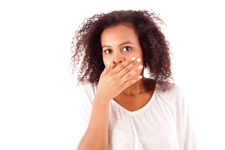 Surprised young african woman with hands over her mouthの写真素材