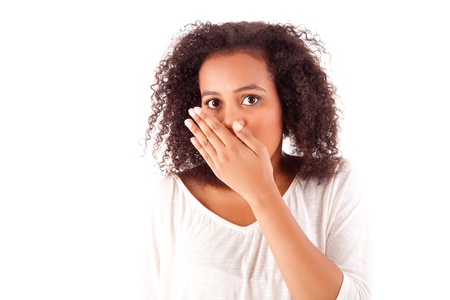 Surprised young african woman with hands over her mouthの写真素材
