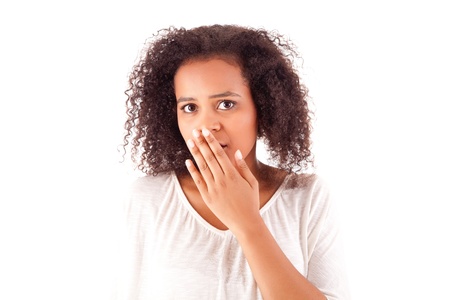 Surprised young african woman with hands over her mouthの写真素材