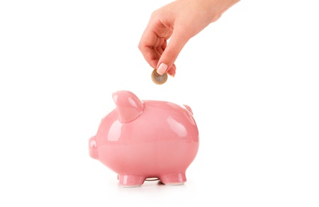 Female hand putting a coin into piggy bankの写真素材