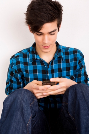 Young man looking at his smart phone while text messagingの写真素材