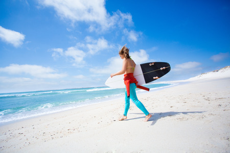 Surfer girl holding a surfboard at the beach