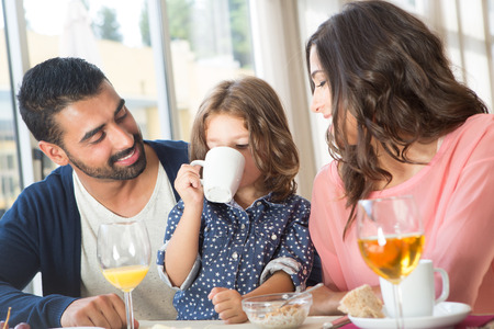 Child having breakfast with her mother and fatherの写真素材