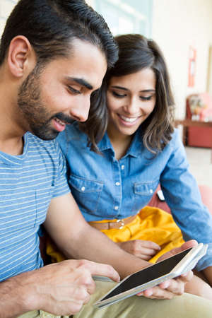 Fashion couple sitting together and using a tabletの写真素材