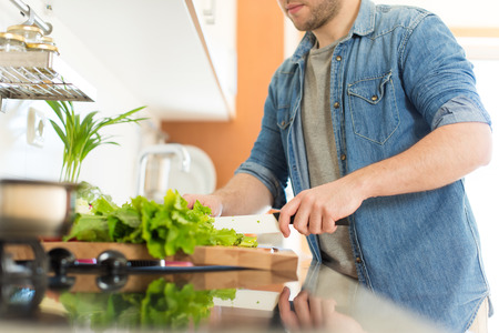 Man cooking and cutting veggies for lunchの写真素材