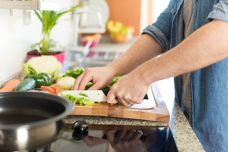 Man cooking and cutting veggies for lunchの写真素材