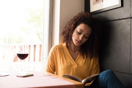 Woman reading book at coffee shopの写真素材