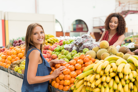 Multi-etchnic women trading organic veggies and fruitsの写真素材