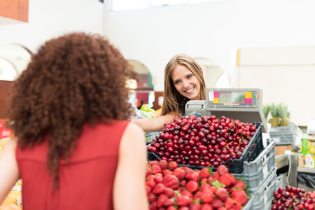 Multi-etchnic women trading organic veggies and fruitsの写真素材