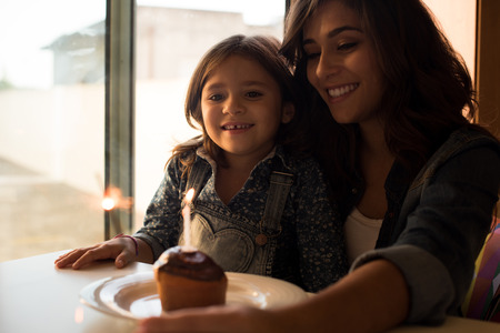 Mother and daughter celebrating birthday with cupcake and sparklersの写真素材