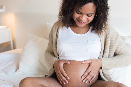 Happy afro woman showing her pregnant belly