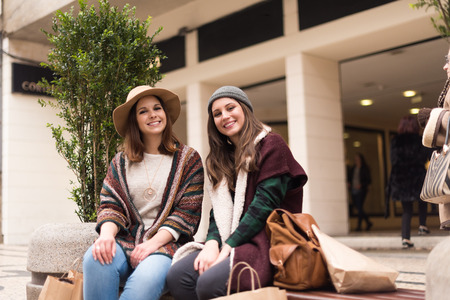 Couple od friends sitting on the city benchの写真素材