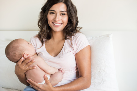 Lovely mother holding newborn baby in armsの写真素材