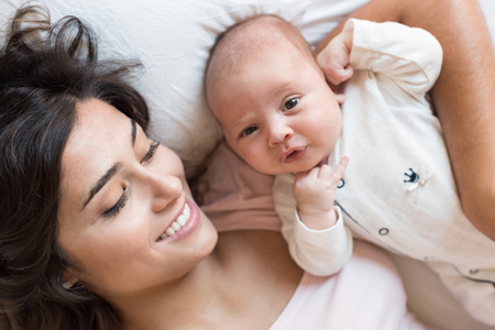Young mother with her baby in bedの写真素材