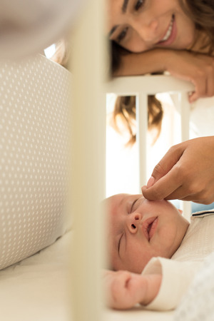 Mother putting baby to sleep at the cribの写真素材