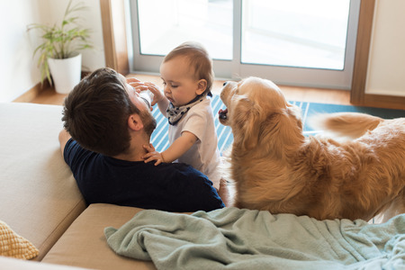 Family having fun with a feeding bottle - Father, baby and dog!の写真素材
