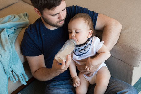 Young father feeding his baby with nursing bottleの写真素材