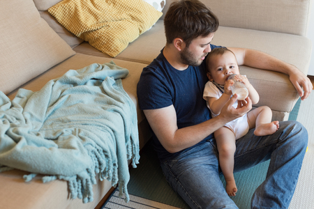 Young father feeding his baby with nursing bottleの写真素材