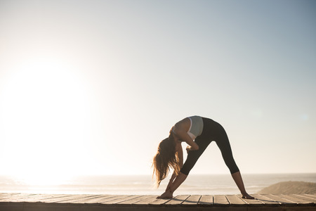 Fitness woman enjoying beautiful sunset on the beachの写真素材