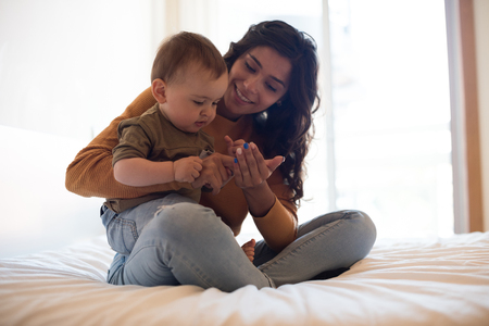 Young mother playing with her baby at homeの写真素材