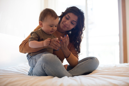 Young mother playing with her baby at homeの写真素材